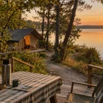 Camping Huttopia lac de l’Uby au bord du lac, vue golden hour depuis une terrasse