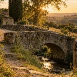 Lieux insolites dans le Gers : pont ancien près d’un ruisseau et tour médiévale au loin