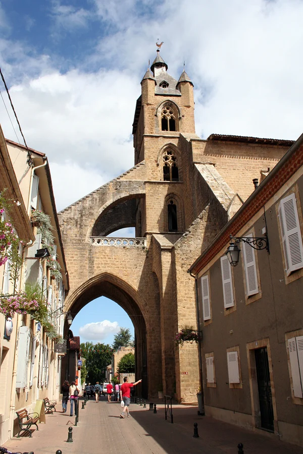 Le porche et le clocher de l’ancienne cathédrale de Mirande au-dessus de la rue, avec les maisons voisines