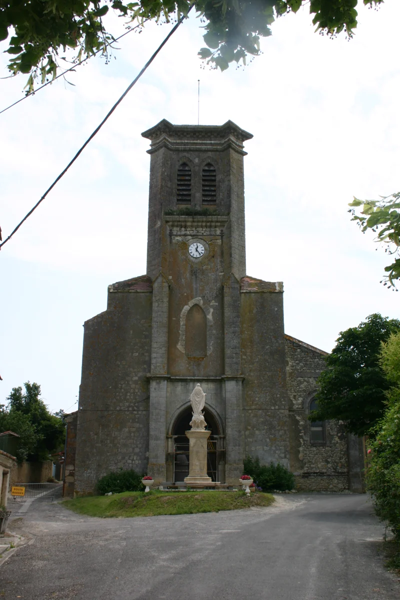 L’église Notre-Dame-de-la-Nativité de Saint-Puy, avec son clocher à horloge et la statue de l’Immaculée Conception sur sa petite place
